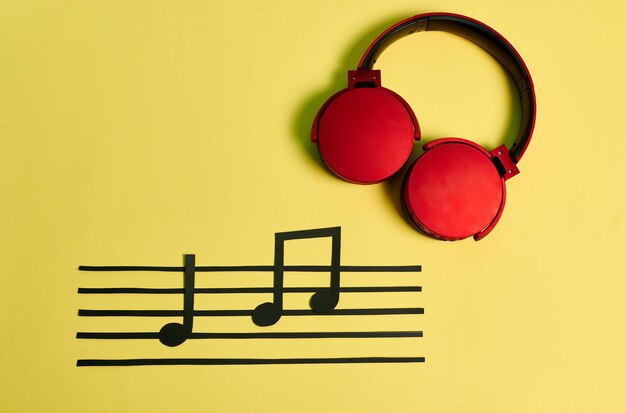 Foto notas de música y auriculares rojos sobre fondo amarillo