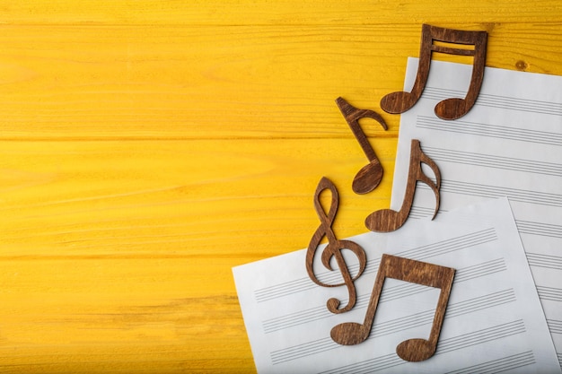 Notas musicales sobre hojas de música sobre fondo de madera amarilla