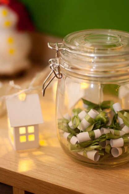 Notas de papel con cintas verdes en un frasco de vidrio en el fondo de las linternas navideñas