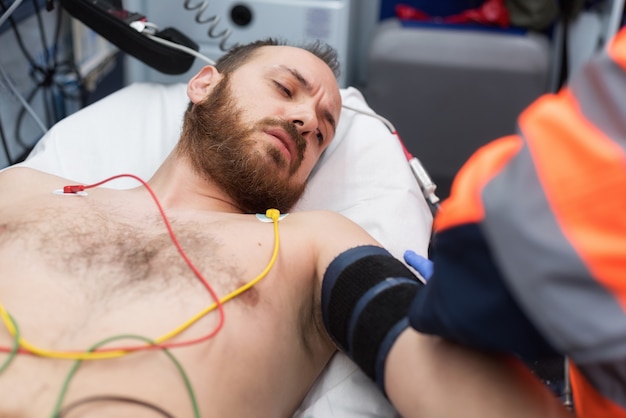 Notdoktor, der Blutdruck eines Patienten im Krankenwagen überprüft