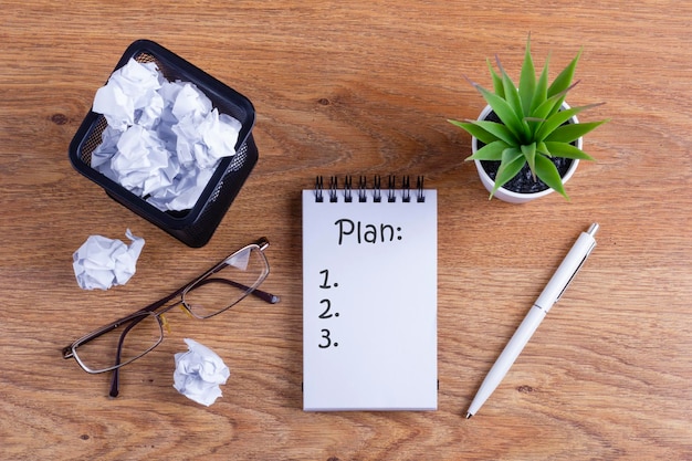 Notebook auf dem Holztisch mit der Aufschrift Plan Businessman's Table Planungskonzept