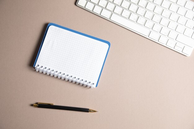 Notebook, caneta e teclado na mesa