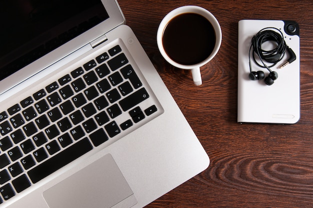 Notebook com café quente na mesa de madeira