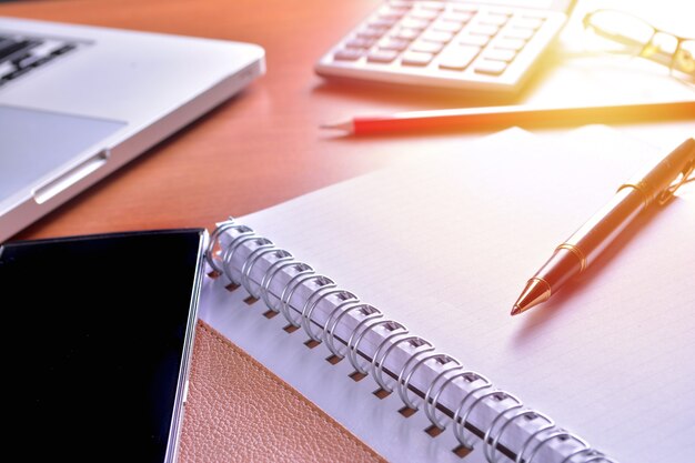 Notebook com calculadora, teclado e caneta na mesa