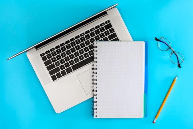Notebook em branco e óculos de olho em uma vista superior de fundo azul