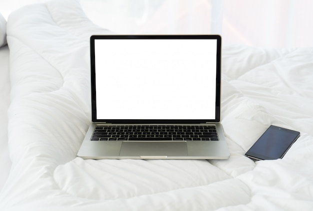 Notebook und Smartphone des leeren Bildschirms auf Bett