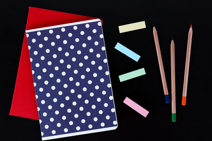 Foto notebooks com lápis coloridos e adesivos em mesa preta