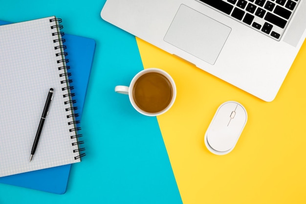 Notebooks laptop e xícara de café em um fundo azul e amarelo