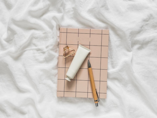 Notepad caneta clip de cabelo creme de mão acessórios femininos elegantes em um estilo minimalista em um fundo claro vista de cima