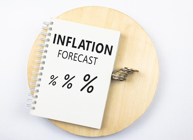 Foto notepadnotebook mit den worten inflationsprognose und zeichenprozentsymbolen auf dem hintergrund von coinsinflation-konzept