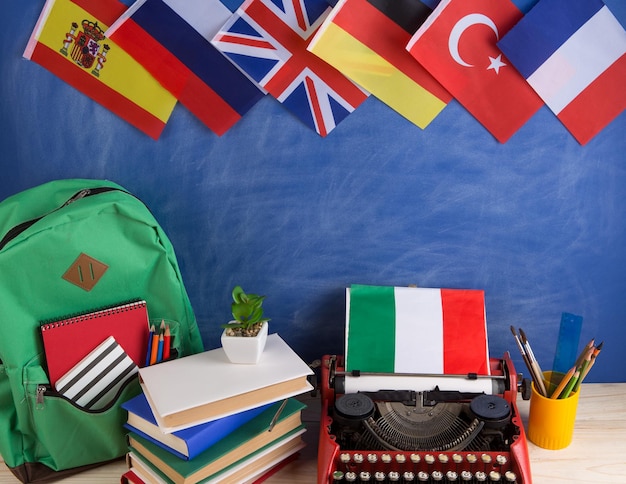 Noticias políticas y educación concepto máquina de escribir roja bandera de Italia y otros países mochila libros papelería