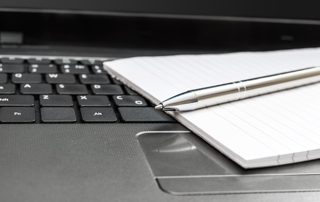 Notizblock mit Stift auf der Laptoptastatur Nahaufnahme