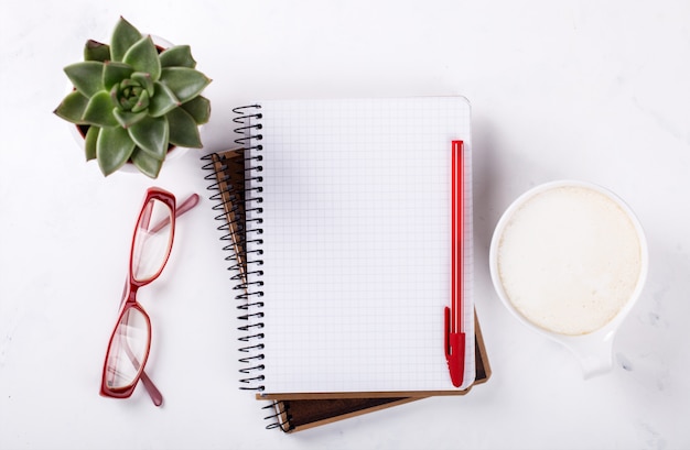 Notizblock mit Stift, Brille, Kaffee und Blume