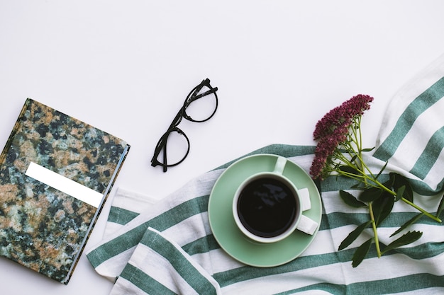 Notizblock und Tasse Kaffee auf weißem Hintergrund.