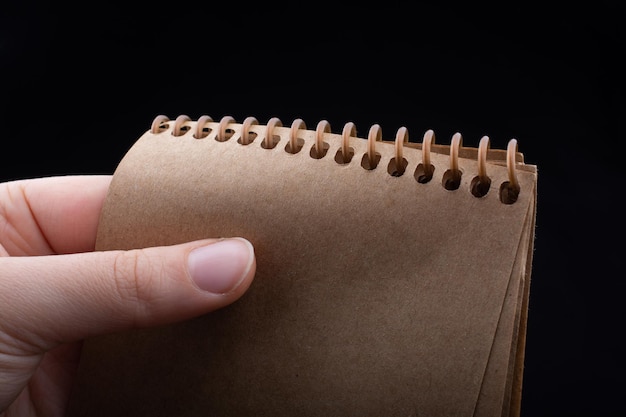 Notizbuch in der Hand auf schwarzem Hintergrund