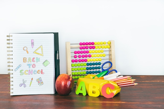 Notizbuch mit Back-to-School-Zeichnung. Schulmaterial mit Abakus, Bleistiften, Buchstaben und einem Apfel. Platz kopieren