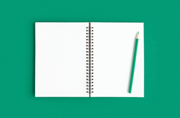 Notizbuch mit Bleistift Öffnen Sie Notizbuch auf grünem smaragdgrünem Farbhintergrund-Spiralnotizblock Draufsicht