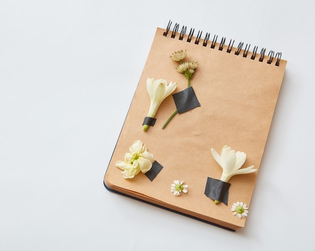 Notizbuch mit Bleistift kann für Ihre Ideen auf grauem Hintergrund verwendet werden. Notizbuchpapier ist mit kleinen Blumen gestaltet.