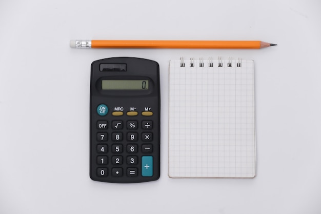 Notizbuch mit Bleistift, Taschenrechner auf weißem Hintergrund. Ansicht von oben