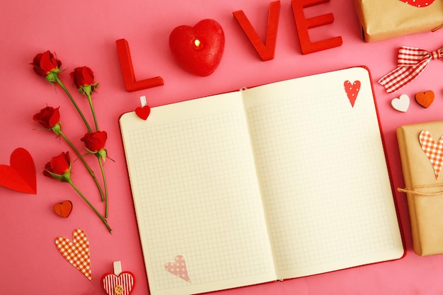 Notizbuch mit Dekor des Geschenks und des Valentinsgrußes auf Draufsicht des rosa Hintergrundes