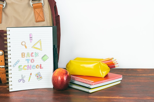 Notizbuch mit zurück zu Schulzeichnung. Rucksack und Schulbedarf mit Apfel auf weißem Hintergrund. Platz kopieren