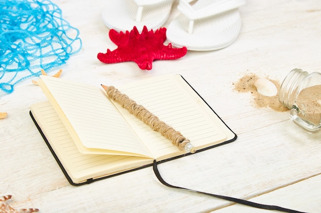 Notizbuch, Seesterne und Muscheln, Glas mit Sand