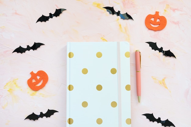 Notizbuch Stift Kürbisse und Fledermäuse auf einem rosa Hintergrund Halloween-Konzept