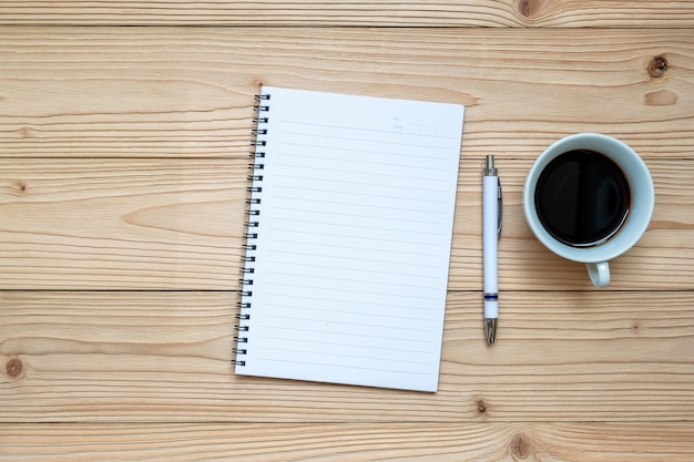 Notizbuch, Stift und schwarzer Kaffee auf hölzernem Hintergrund. Geschäfts- und entspannende Konzepte