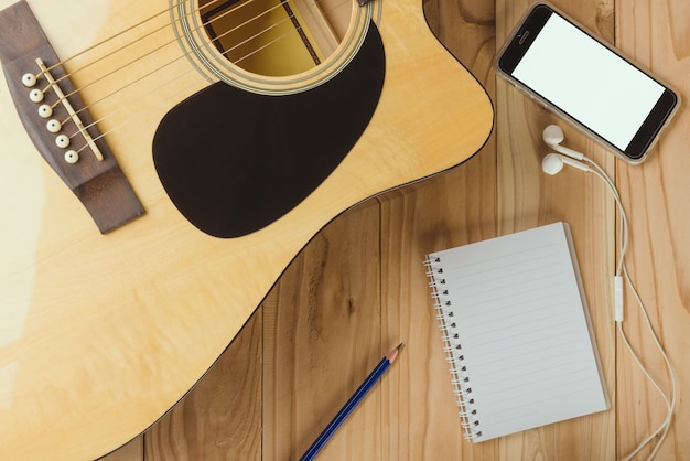 Notizbuch und Bleistift auf Gitarre, Musik schreibend