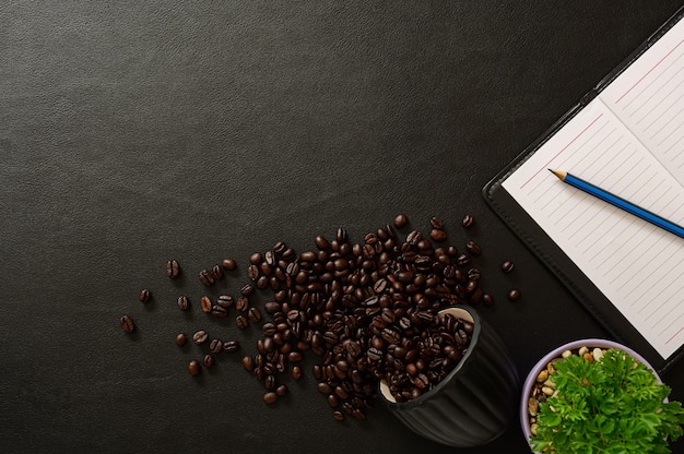 Notizbuch und Kaffeebohnen werden auf den Schreibtisch gelegt