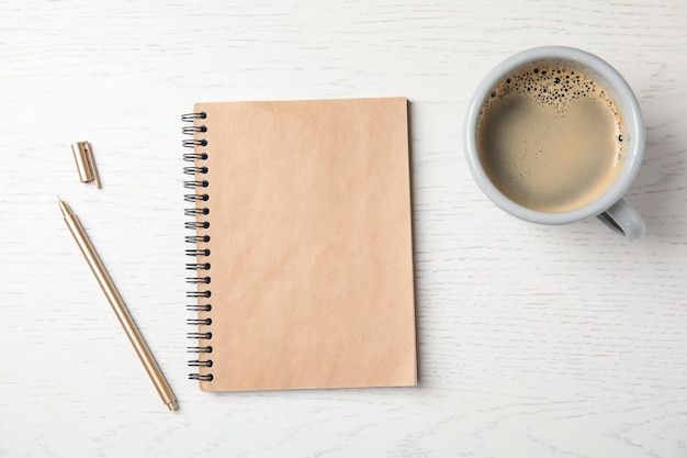 Notizbuch und Tasse Kaffee auf Draufsicht des hölzernen Hintergrundes