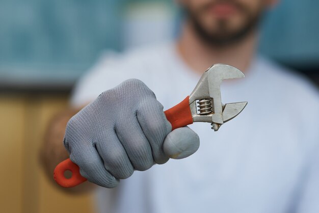 Notwendiges Handwerkzeug Nahaufnahme der Hand eines jungen Mechanikers, der einen verstellbaren Schraubenschlüssel hält