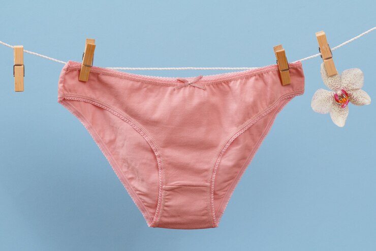 Foto nova calcinha de algodão rosa no varal com prendedores de roupa e flor de orquídea em fundo azul. roupa interior de mulher.