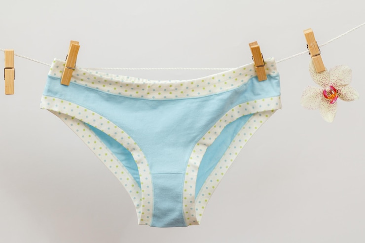 Foto nova calcinha no varal com prendedores de roupa e flor de orquídea em fundo branco roupa íntima feminina