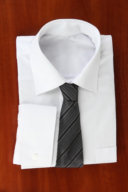 Nova camisa do homem branco com gravata colorida em fundo de madeira