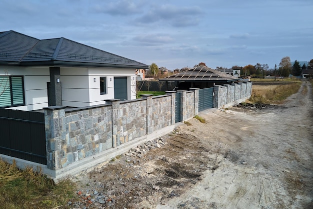 Nova casa residencial e garagem anexa com grande quintal cercado pavimentado em dia ensolarado na área suburbana moderna Conceito de propriedade imobiliária