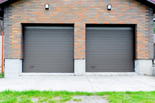 Foto nova garagem de estacionamento em casa de tijolos de luxo para construção de dois carros com persianas nos portões