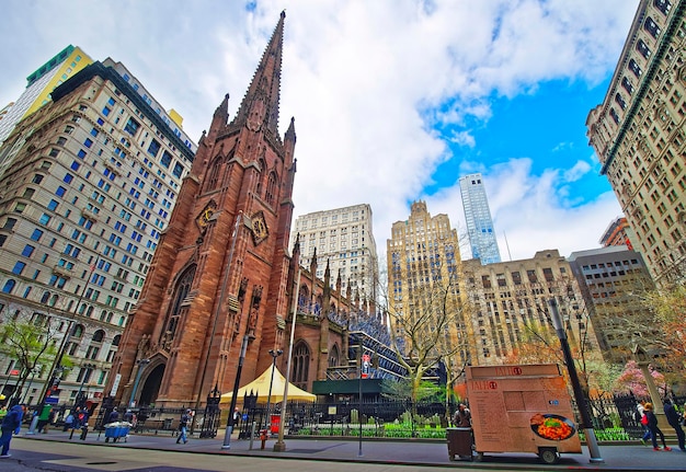 Nova York, EUA - 24 de abril de 2015: Vista da rua da Igreja da Trindade em Lower Manhattan, Nova York, EUA. É uma igreja paroquial histórica perto de Wall Street e Broadway. Turistas nas proximidades