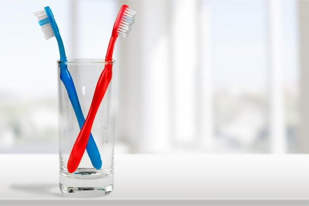 Foto novas escovas de dentes coloridas em um copo no fundo