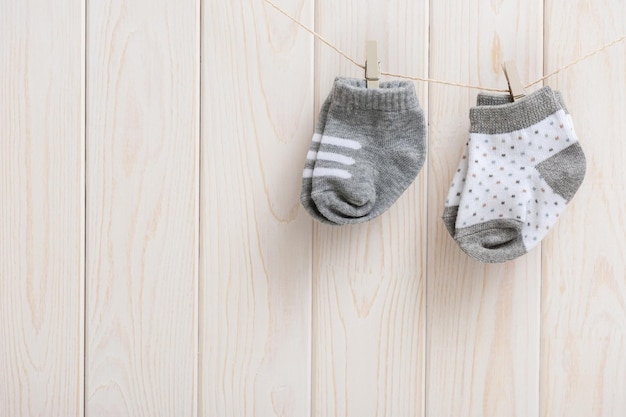 Novas meias de bebê penduradas no varal sobre fundo de madeira recém-nascido e conceito de bebê