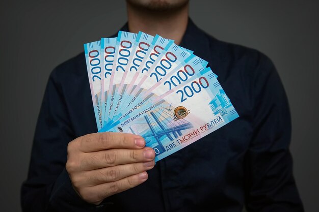 Novas notas russas denominadas em 2000 rublos em mãos masculinas fechadas em cinza