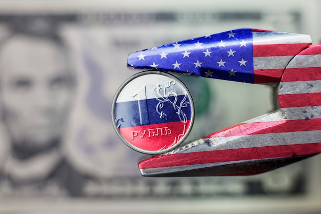 Novas sanções contra a economia russa. Alicate com bandeira EUA espremido o rublo com bandeira russa.
