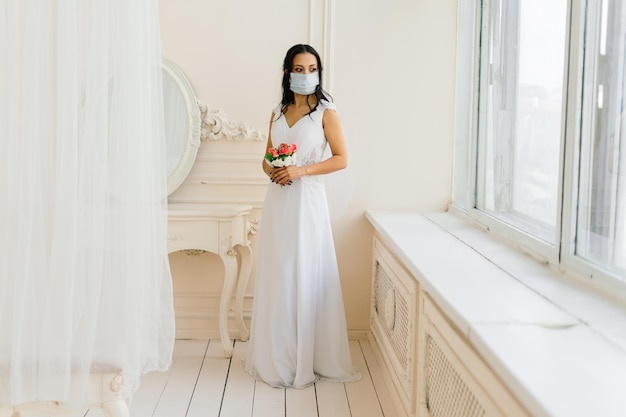 Novia afroamericana vestida, máscara y por la mañana preparándose para la boda en la habitación del hotel