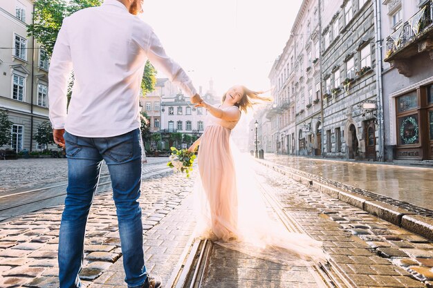 La novia alegre camina con el novio por las calles de la c