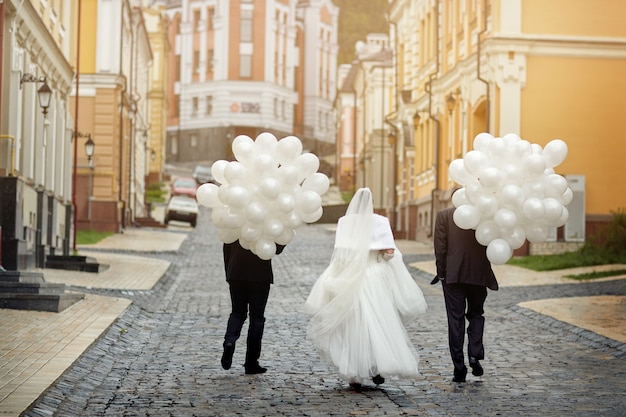 La novia y los amigos van a la distancia con una gran cantidad de globos.