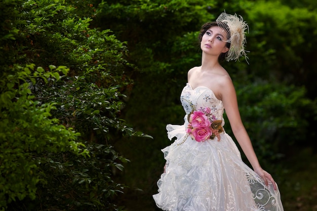 Novia atractiva en vestido blanco en el parque