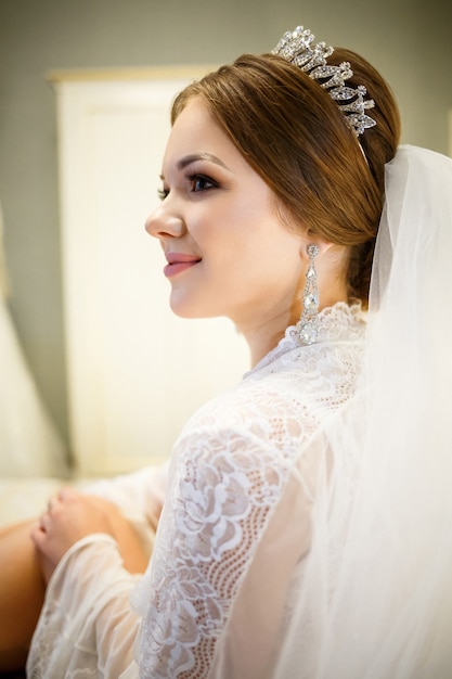 La novia con una bata blanca en la cama en una mañana de bodas