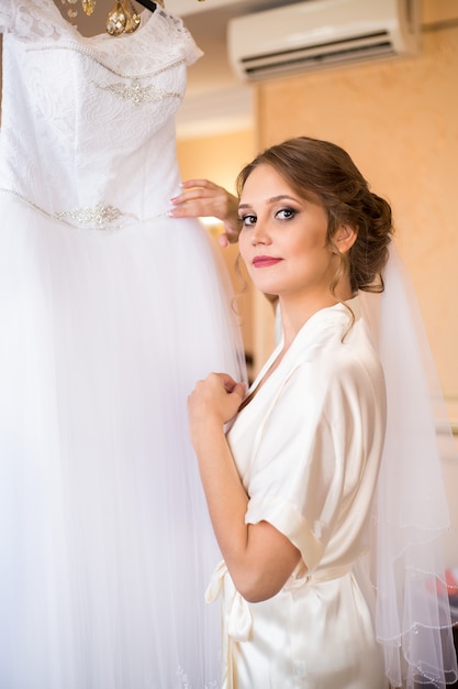 Una novia en bata viene a su vestido de novia