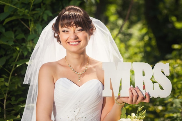 Foto novia de belleza en el bosque de verano con signo mrs