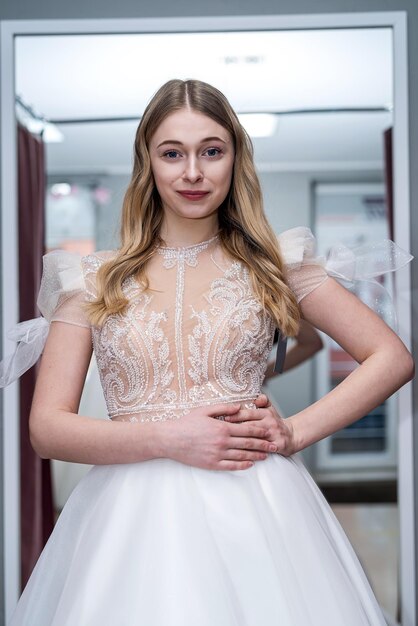 La novia bonita elige el mejor vestido elegante de boda en el salón